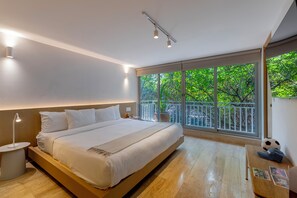 A modern bedroom with a large bed, bedside tables, a nightstand, a window with a view of greenery, and a balcony. - Casa Hugo by Capitalia (Mexico City)