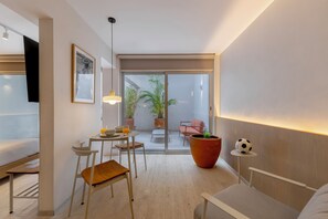 A modern room with a bed, a desk, a chair, a table with a plant, and a sliding glass door leading to an outdoor area with a chair and a plant. - Casa Hugo by Capitalia (Mexico City)