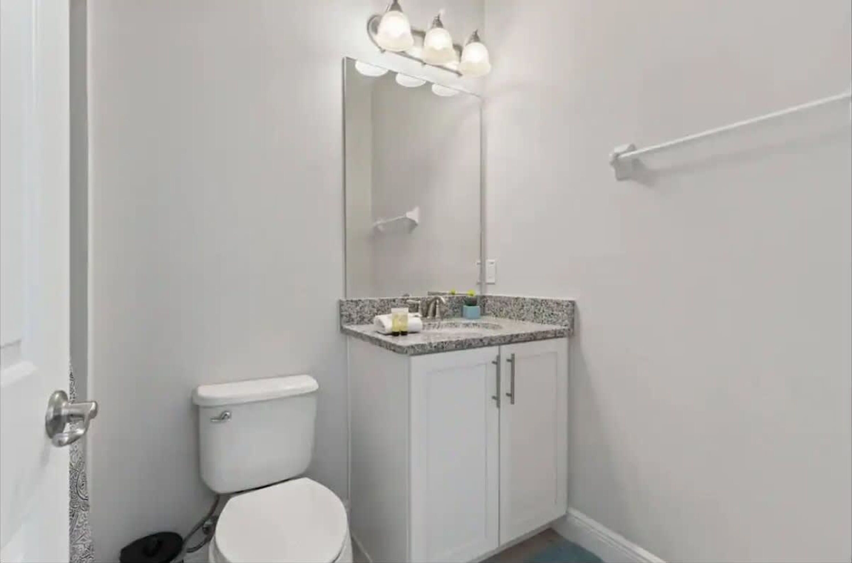 A bathroom with a toilet, a sink with a mirror above it, and a towel rack on the wall.