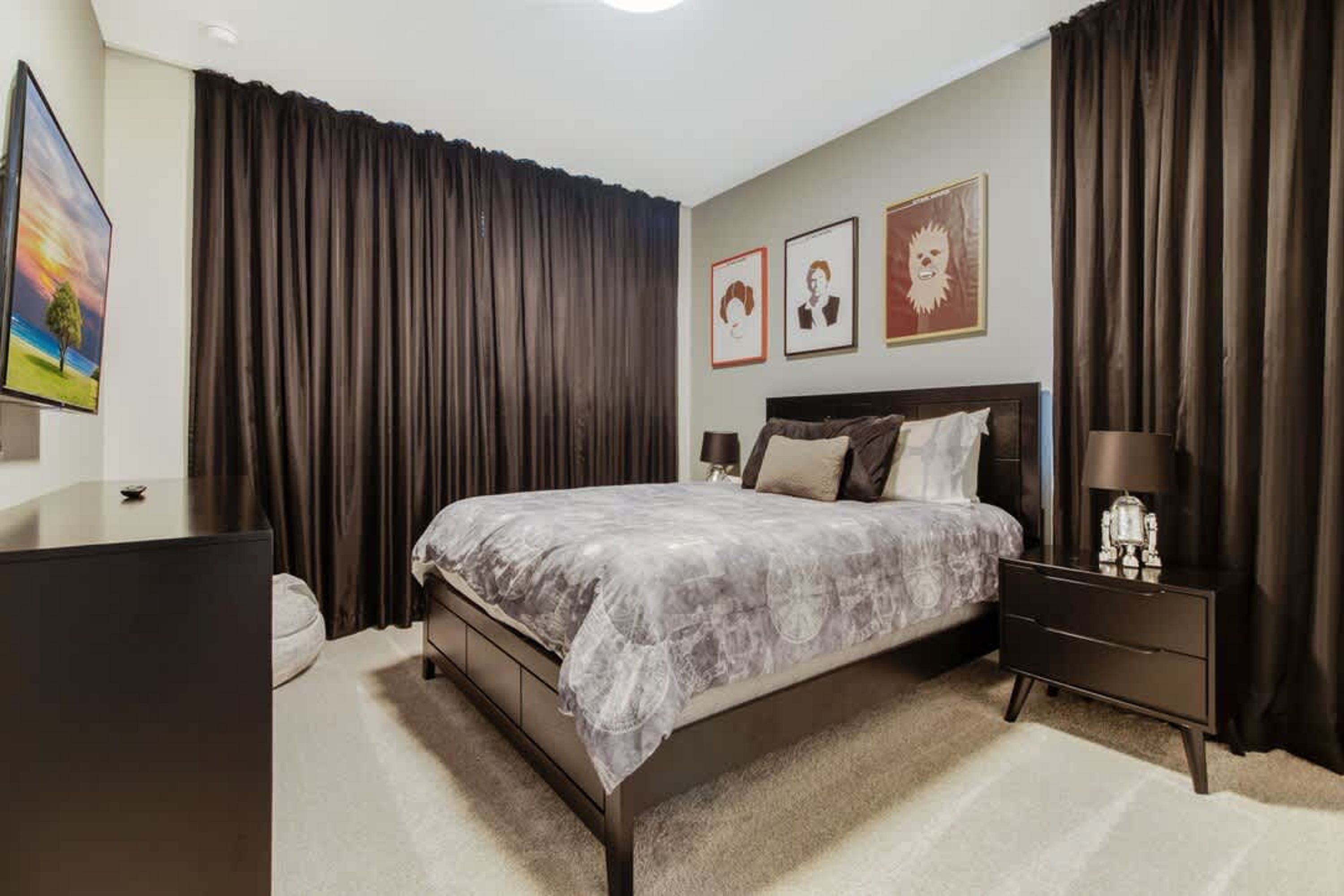 Un dormitorio con cama, mesita de noche, lámpara y cómoda.