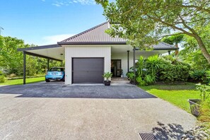 Ein modernes Haus mit Garage, überdachter Auffahrt und üppiger Bepflanzung.