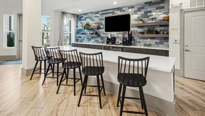 Uma cozinha moderna com uma ilha grande, banquetas e uma televisão de tela plana.