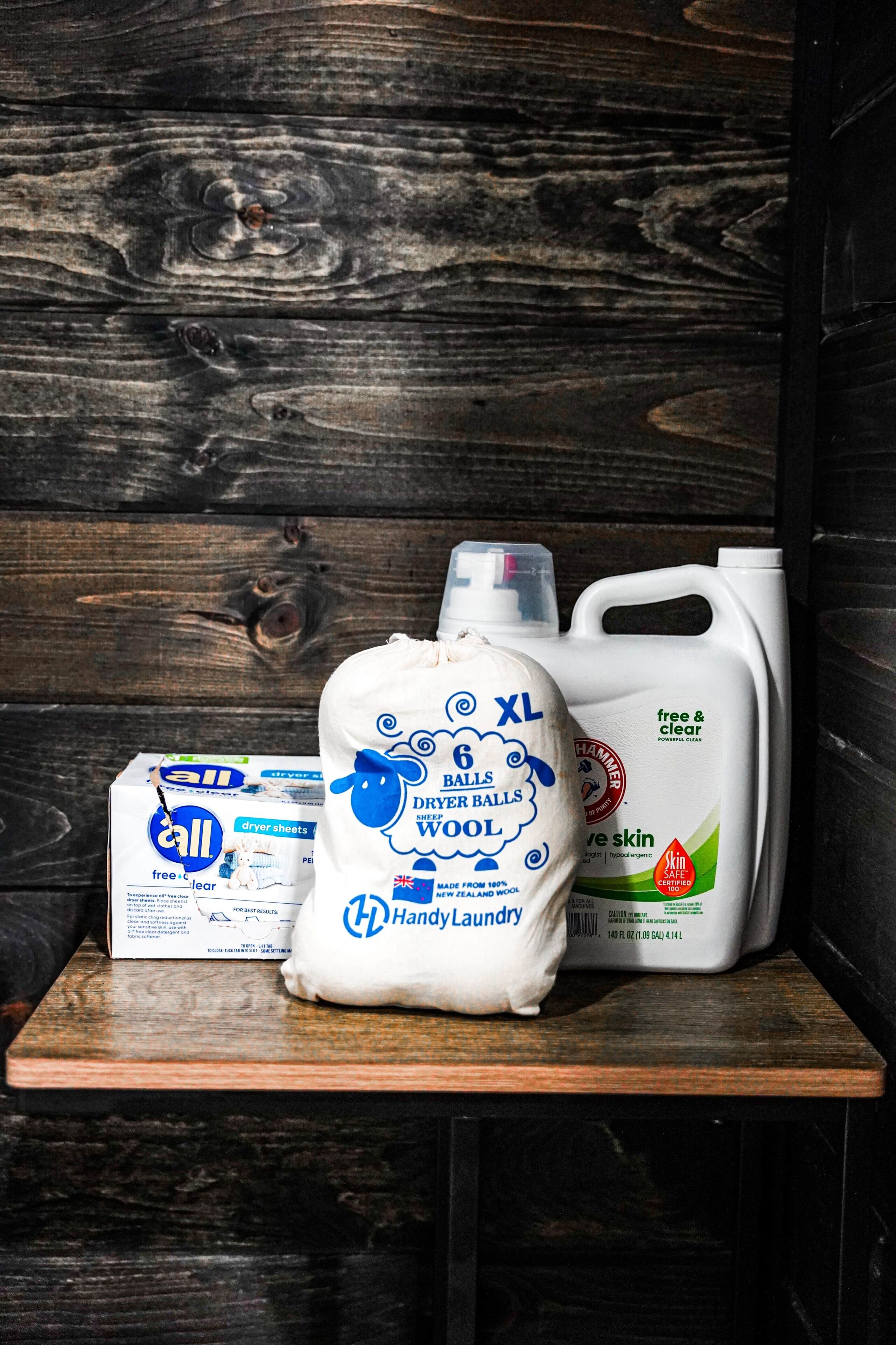 Een plank met een doos wasverzachter, een fles wolwasmiddel en een gallon reiniger voor de huid.