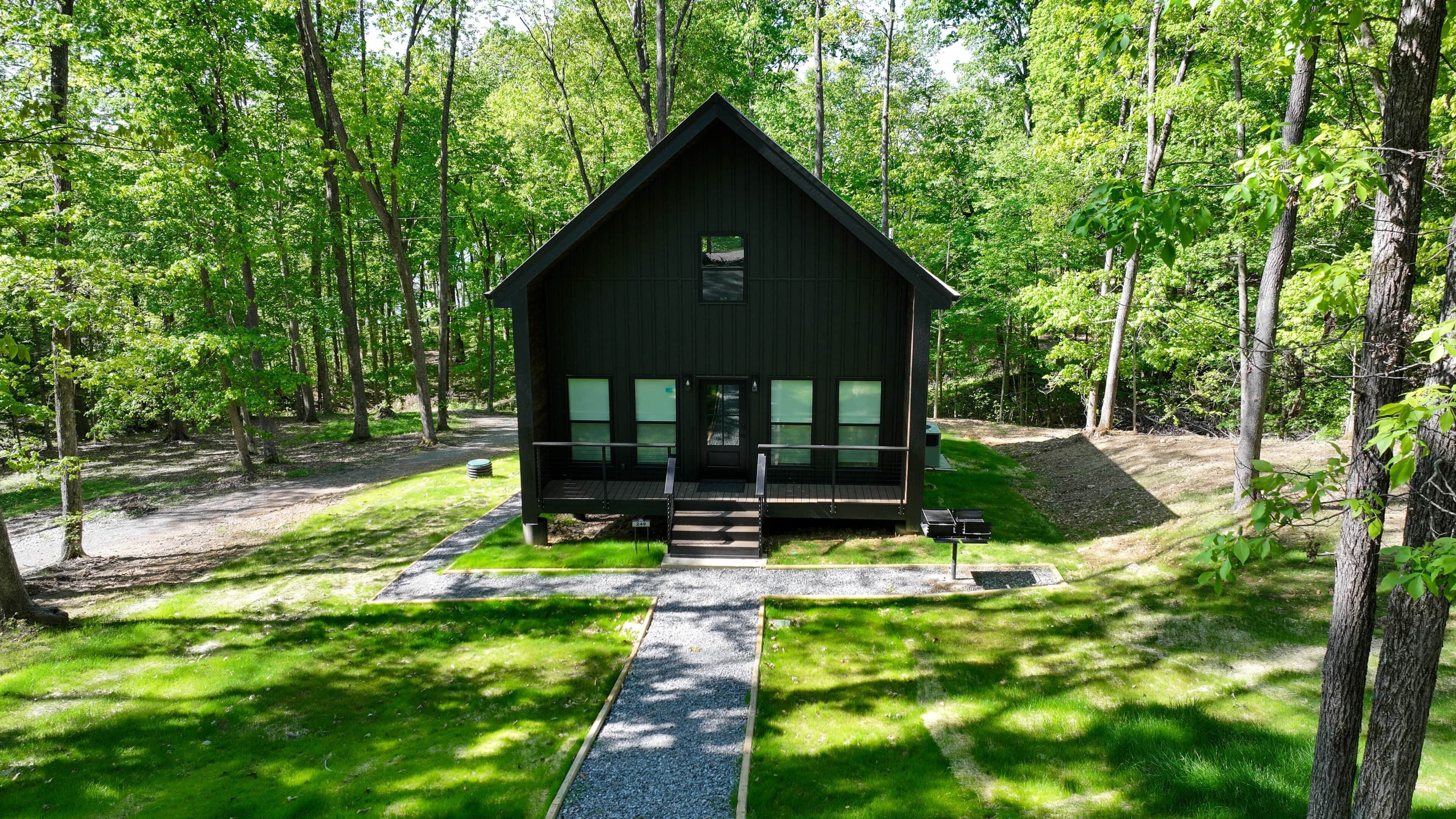A cabin with a porch, surrounded by trees.
