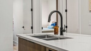 A modern kitchen with a double sink, a bottle of soap, and a wooden cabinet. - Modern, spacious 2BR suite in Calgary, 13 min to downtown, private entrance (Calgary)