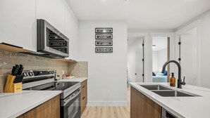 A modern kitchen with a stove, oven, and sink, wooden cabinets, and a backsplash. - Modern, spacious 2BR suite in Calgary, 13 min to downtown, private entrance (Calgary)