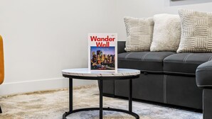 A book titled 'Wander Well' on a small round table in a living room with a black sofa and decorative pillows. - Modern, spacious 2BR suite in Calgary, 13 min to downtown, private entrance (Calgary)