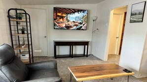 Uma sala de estar com sofá, mesa de centro, televisão e estante de livros.