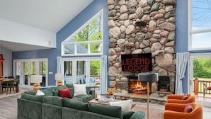 Una sala de estar con chimenea de piedra, sofás verdes y un letrero que dice 'The Legend Lodge'.