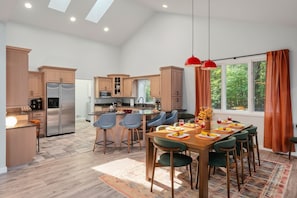 Une cuisine moderne avec un coin repas, des meubles en bois et une grande fenêtre agrémentée de rideaux.