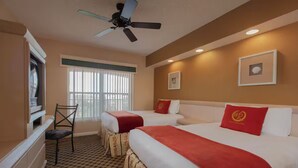 A hotel room with two beds, a ceiling fan, a television, a chair, and a window with blinds. - Westgate town center resort / 2 bedrooms (Kissimmee)