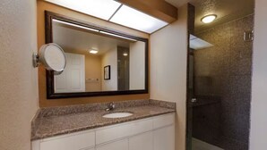 A bathroom with a granite countertop sink, a large mirror, and a glass-enclosed shower. - Westgate town center resort / 2 bedrooms (Kissimmee)