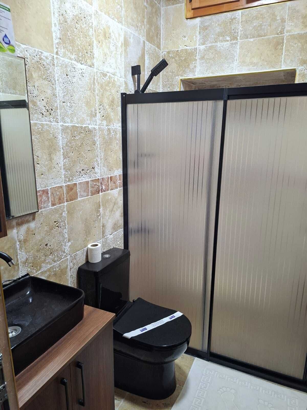 A bathroom with a sink, toilet, and a shower enclosure.