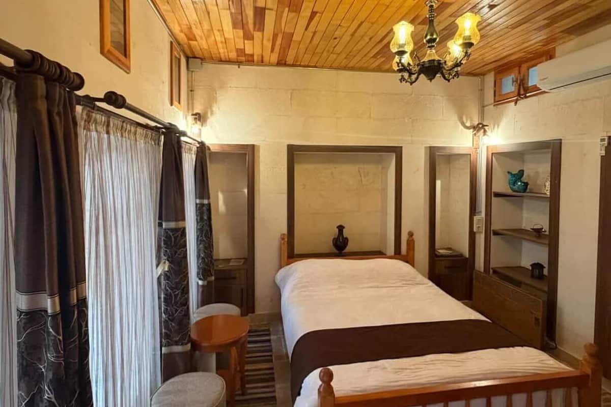 Une chambre à coucher avec un plafond en bois, un lit, une chaise, une petite table et une table de chevet.