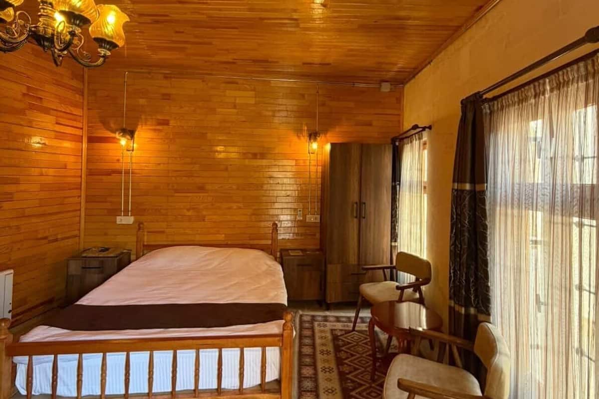 Une pièce aux murs lambrissés, contenant un lit, un bureau et une chaise.