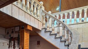 A curved staircase with balustrades, a wooden bench, and a door with a sign. - Ela Sultan Han (Gaziantep)