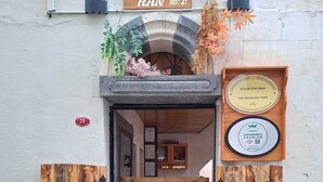 A rustic entrance with a wooden gate, a sign above reading 'ELA SULTAN HAN NO: 21', and a plaque indicating sustainable tourism certification. - Ela Sultan Han (Gaziantep)