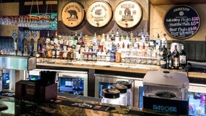 Een bar met verschillende drankflessen, een bord met 'whiskeyproeverij' en een bord met 'Jameson'.