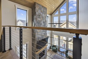 Un intérieur spacieux avec une cheminée en pierre, de grandes fenêtres et un plafond en bois.