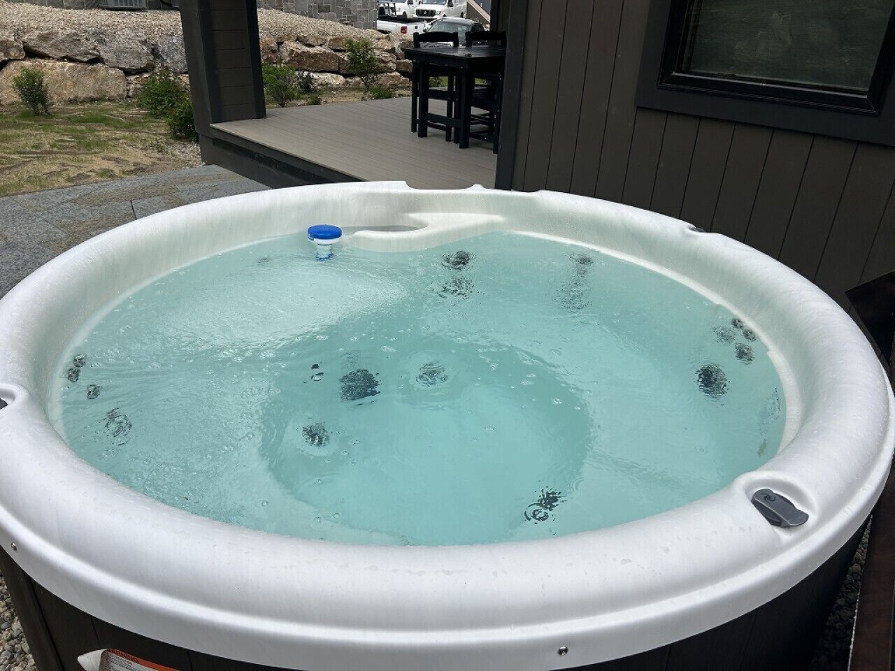 A hot tub with a control panel, surrounded by a deck and outdoor furniture.
