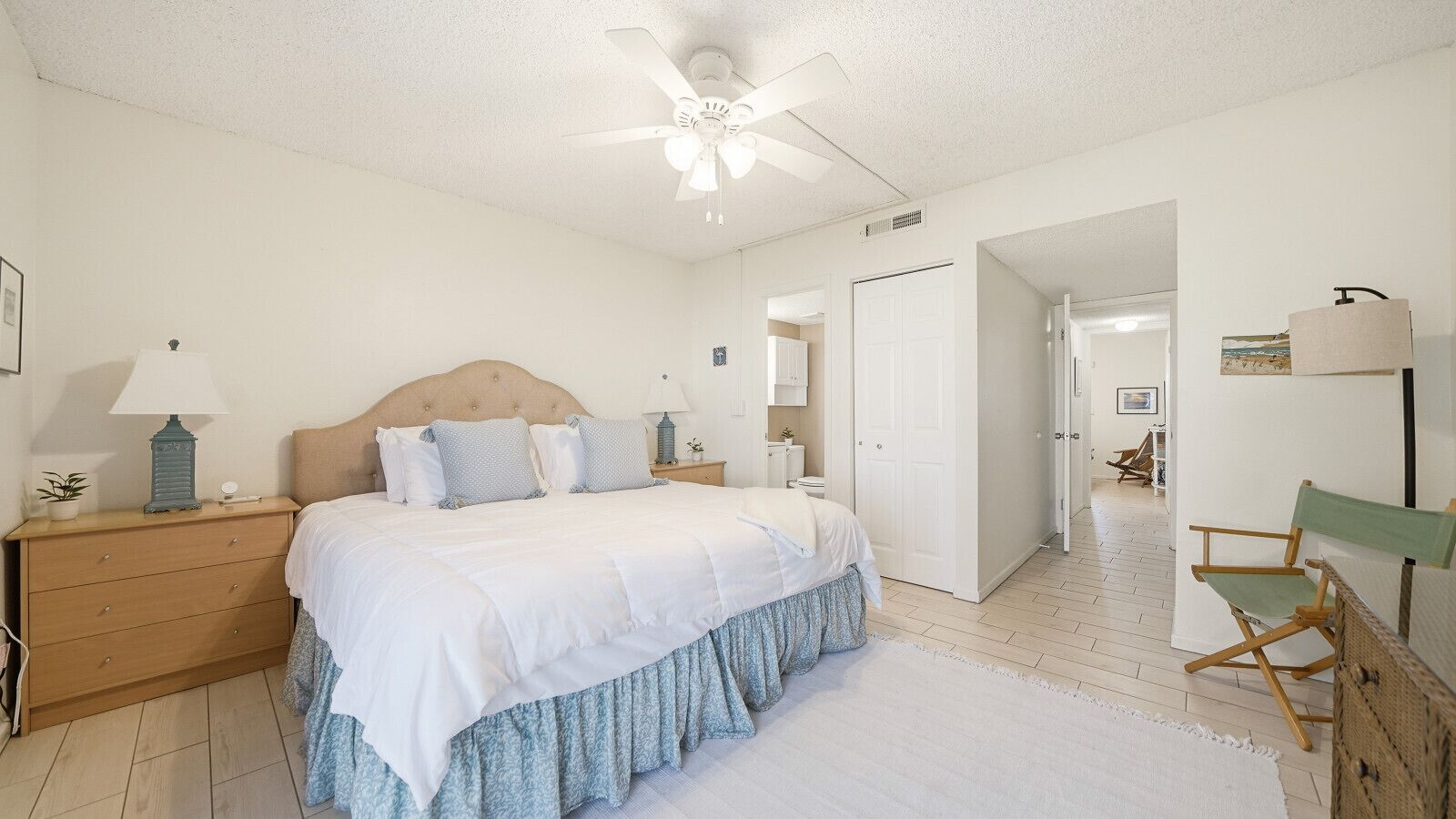 A bedroom with a bed, nightstands, a ceiling fan, a dresser, and a chair.