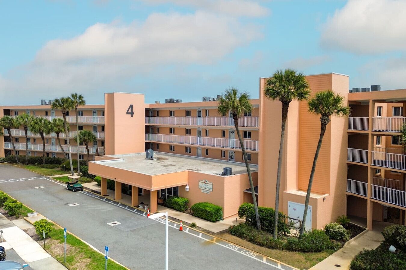 A multi-story hotel with a flat roof, numbered '4', and a parking lot in front.