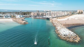 Hotel a la costa amb un port esportiu, vistes al mar i un tram de costa rocosa.
