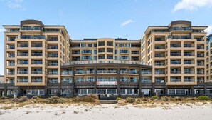 Un hotel de diverses plantes amb entrada central, balcons i vistes a la platja.