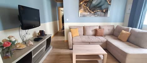 A living room with a TV, sofa, coffee table, and artwork on the wall.