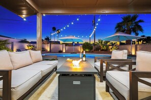 An outdoor patio with a pool, lounge chairs, and string lights. - Casa Calypso: Resort Vibes, Games, Massive Parking (Lake Havasu City)