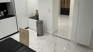 A modern kitchen with white cabinets, a marble floor, and a dining area with a black table. - Peaceful and spacious T3 in the heart of Bordeaux (Bordeaux)