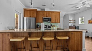 A kitchen with wooden cabinets, stainless steel appliances, and a bar stool seating area.