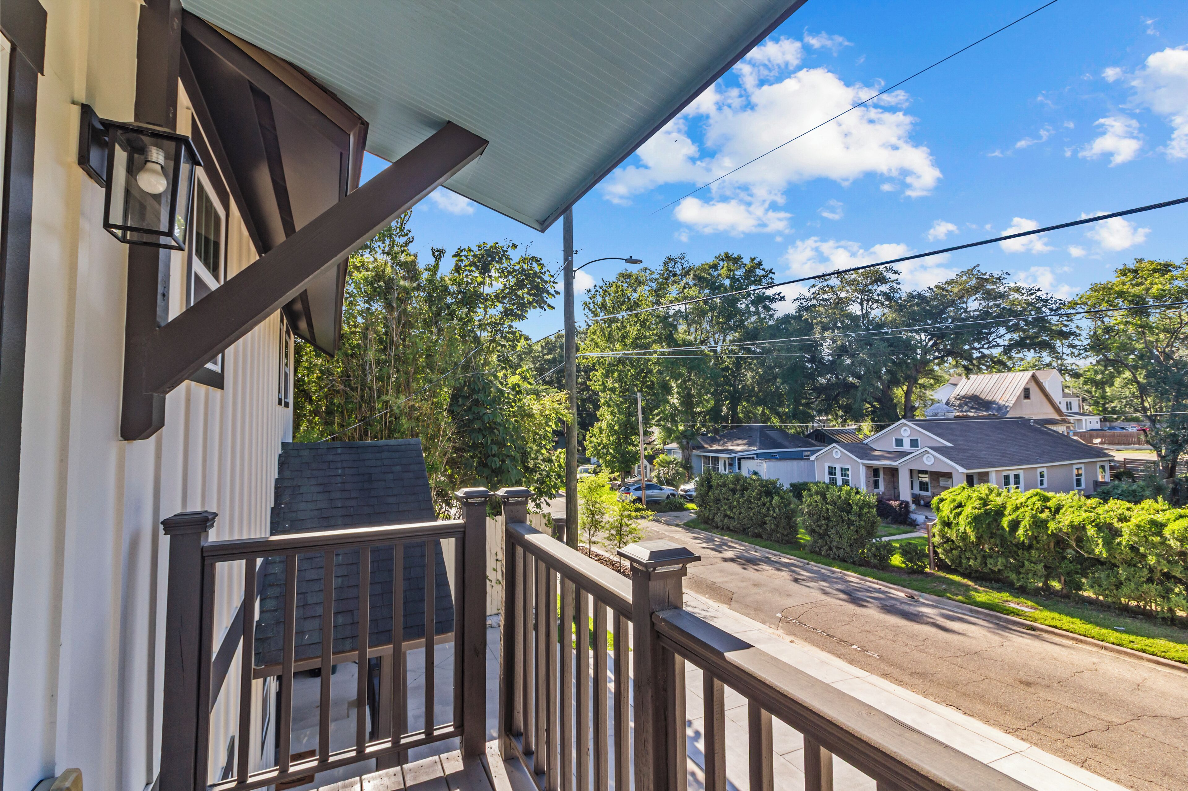 A residential street with houses, a clear sky, and a balcony with a railing.