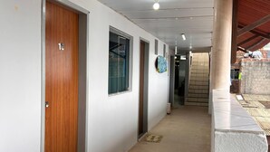 A hallway with white walls, wooden doors, and a tiled floor. - Pousada Recanto Paradise  (Ipojuca)