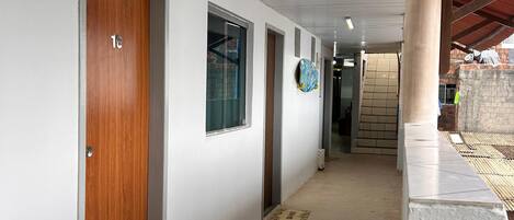 A hallway with white walls, wooden doors, and a tiled floor.