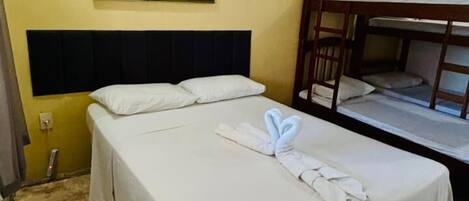 A hotel room with a bed, a bunk bed, a painting on the wall, and a rug.