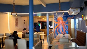 A restaurant interior with tables, chairs, a bar area, and a large octopus mural on the wall. - Pousada Recanto Paradise  (Ipojuca)
