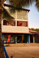 A two-story building with a beach-themed restaurant sign, large windows, and a red-tiled roof.