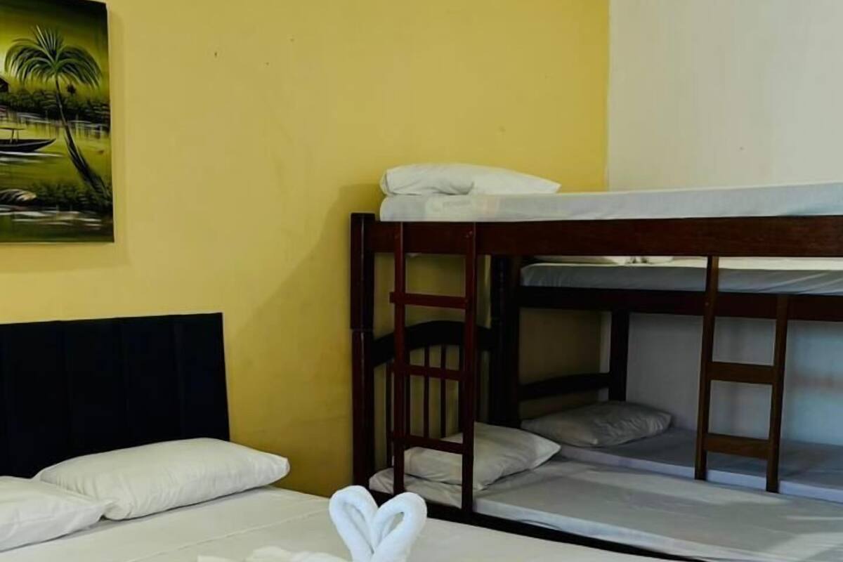 Ένα δωμάτιο ξενοδοχείου με ένα μονό κρεβάτι, ένα διπλό κρεβάτι και έναν πίνακα στον τοίχο.