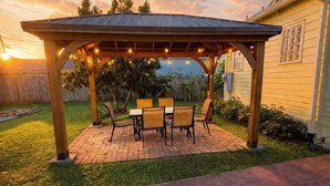 Eine überdachte Terrasse mit Backsteinboden, einer Holz-Pergola und Gartenmöbeln.
