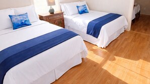 Ein Schlafzimmer mit zwei Betten, einem Deckenventilator, einem Fenster mit Jalousien und einem Bild an der Wand.