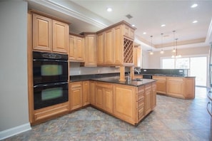 A kitchen with wooden cabinets, a built-in oven, and a large island with a sink.
