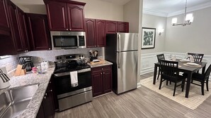 A modern kitchen with stainless steel appliances, dark wooden cabinets, and a dining area with a table and chairs. - Spacious Corporate Furnished One Bedroom/One Bath in Alpharetta. (Alpharetta)