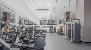 A modern gym with multiple treadmills, weight machines, and a mezzanine level. - Chic 1BR in District 225 / Sleeps 4 (Miami)