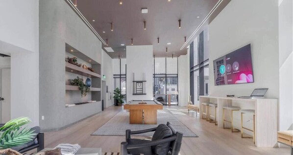 A spacious lobby with a pool table, seating area, and a large TV screen. - Chic 1BR in District 225 / Sleeps 4 (Miami)