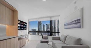 Una sala moderna con vistas a la ciudad, un sofá, una mesita y un televisor.