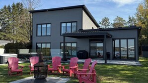 Ein modernes Haus mit Terrasse, Sitzgelegenheit im Freien und Grill.