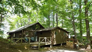 A rustic cabin with a porch, surrounded by trees. - Cozy Adirondack Cabin-Lakeside Resort Camp 1 (Olmstedville)