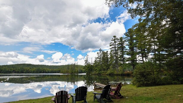 A lakeside view with Adirondack chairs and a dock. - Cozy Adirondack Cabin-Lakeside Resort Camp 1 (Olmstedville)