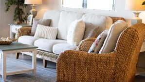 Ein Wohnzimmer mit Sofa, Sessel, Couchtisch und Lampen.